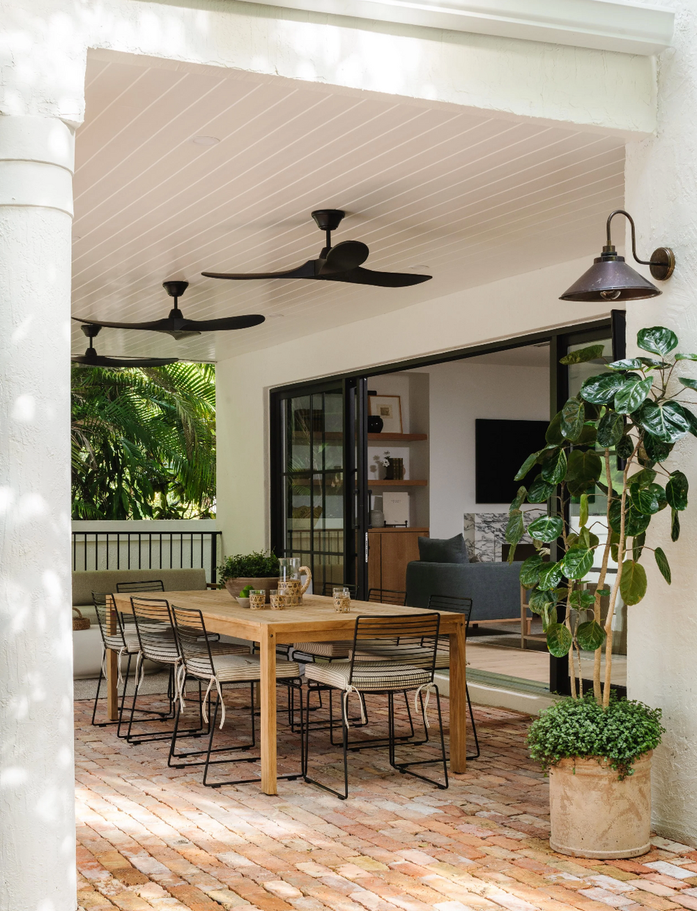 Outdoor dining room with teak table, woven chairs, and potted fiddle leaf fig in Coconut Grove