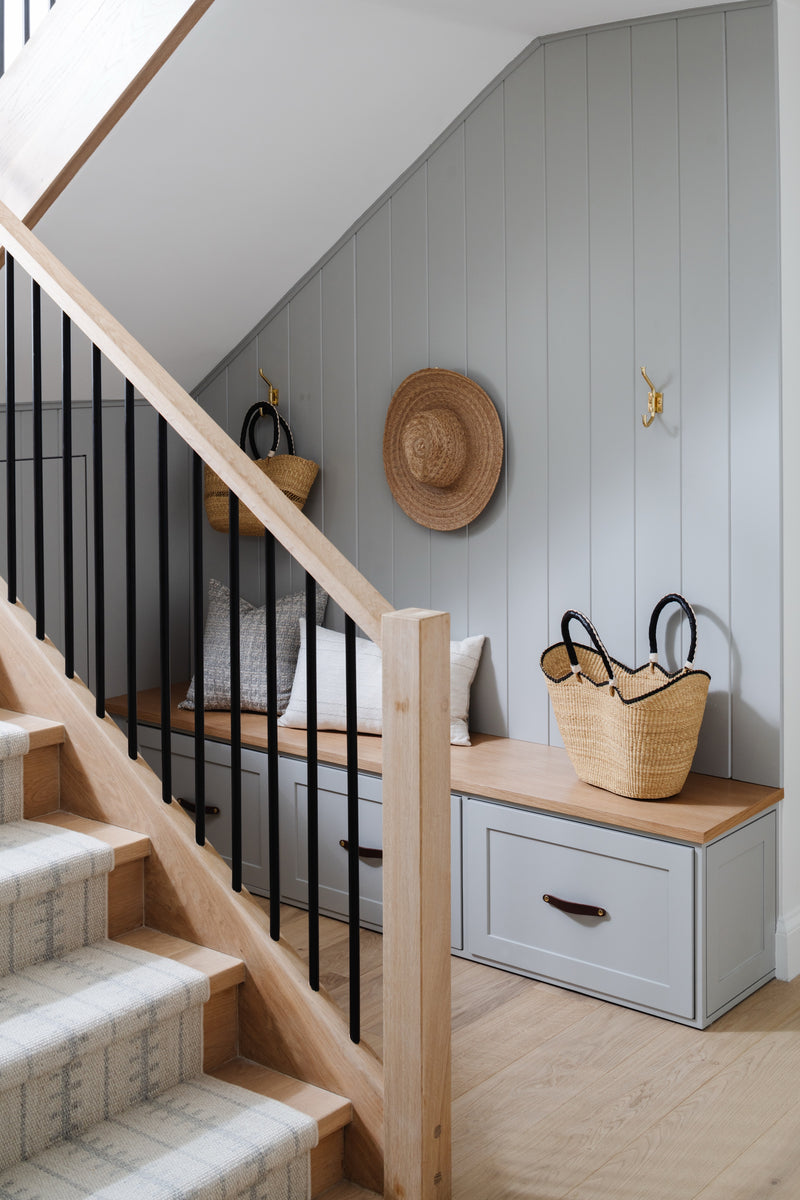 Stairway with oak banister, black spindles, and built-in bench with woven baskets