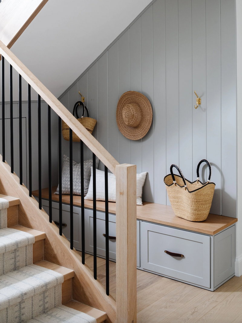 Stairway with oak banister, black spindles, and built-in bench with woven baskets