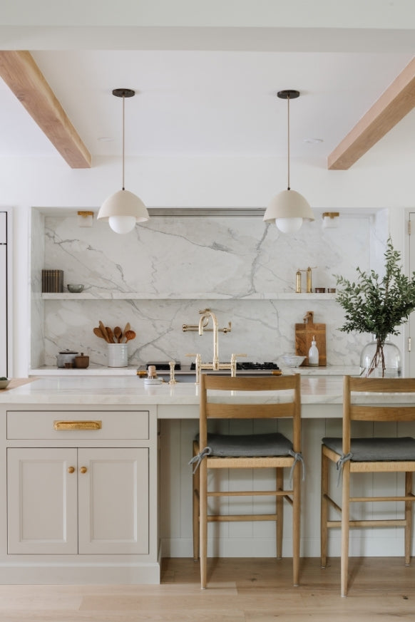 White kitchen with marble slab backsplash, dome pendants, and oak counter stools in the Raynolds Residence