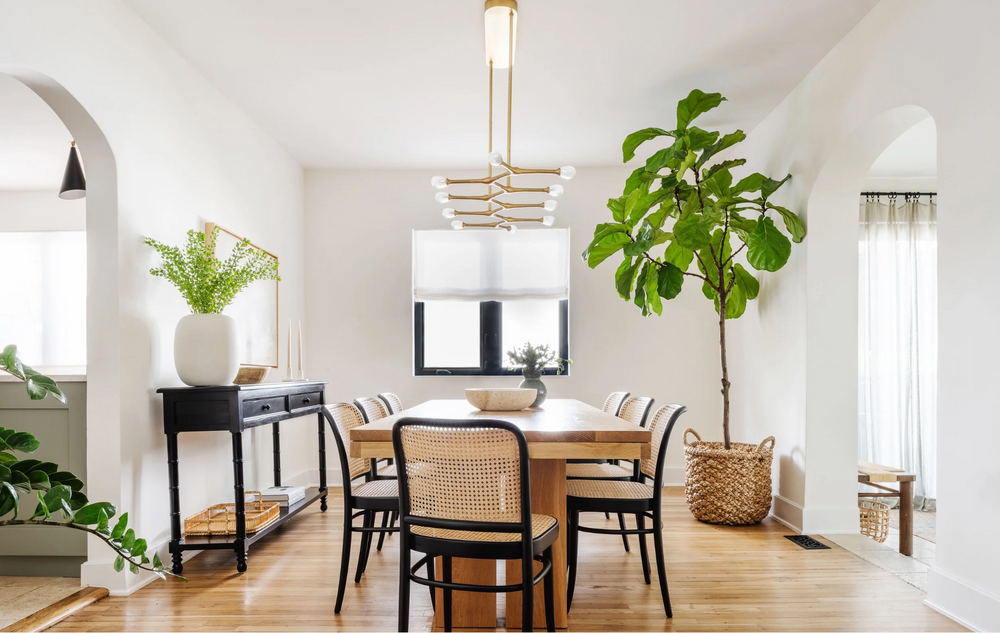 Bright dining room with cane-back chairs, brass linear chandelier, and arched openings