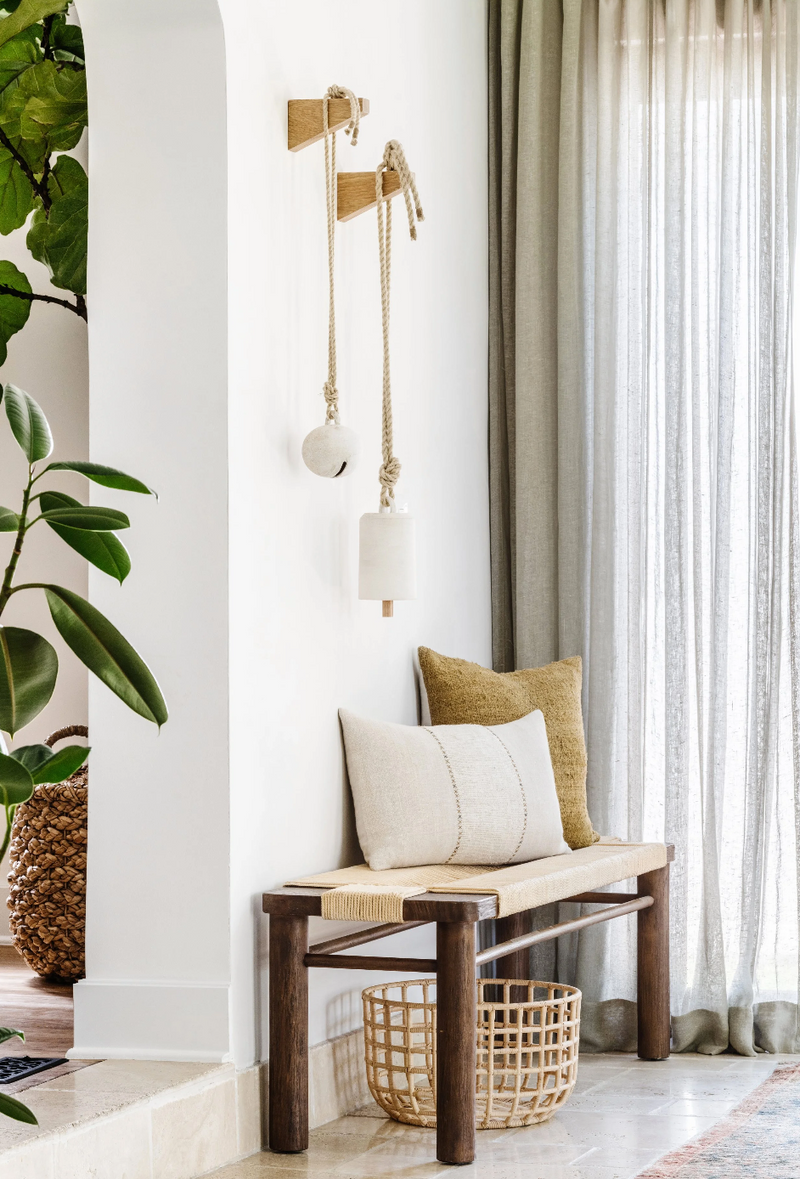 Entry bench with layered pillows and brass sconces in the Spanish in the Gables remodel