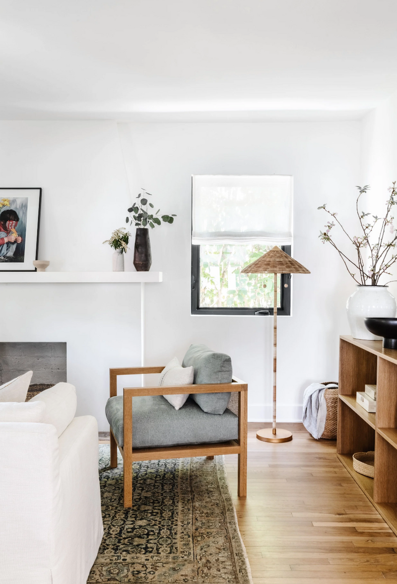 Living room corner with upholstered oak armchair, rattan floor lamp, and vintage rug