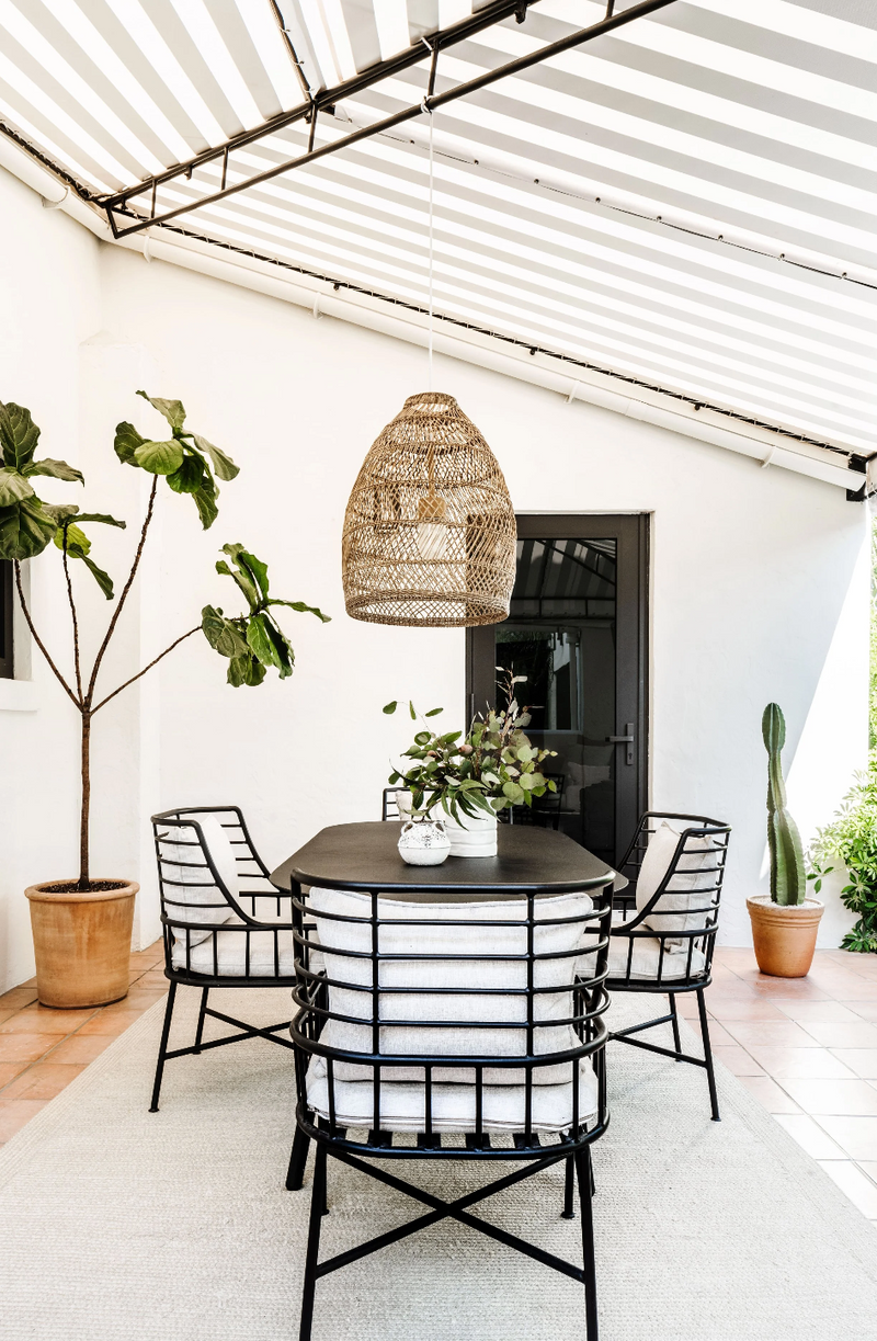 Striped canopy shades an outdoor dining patio with woven pendant and terracotta pots, Coral Gables
