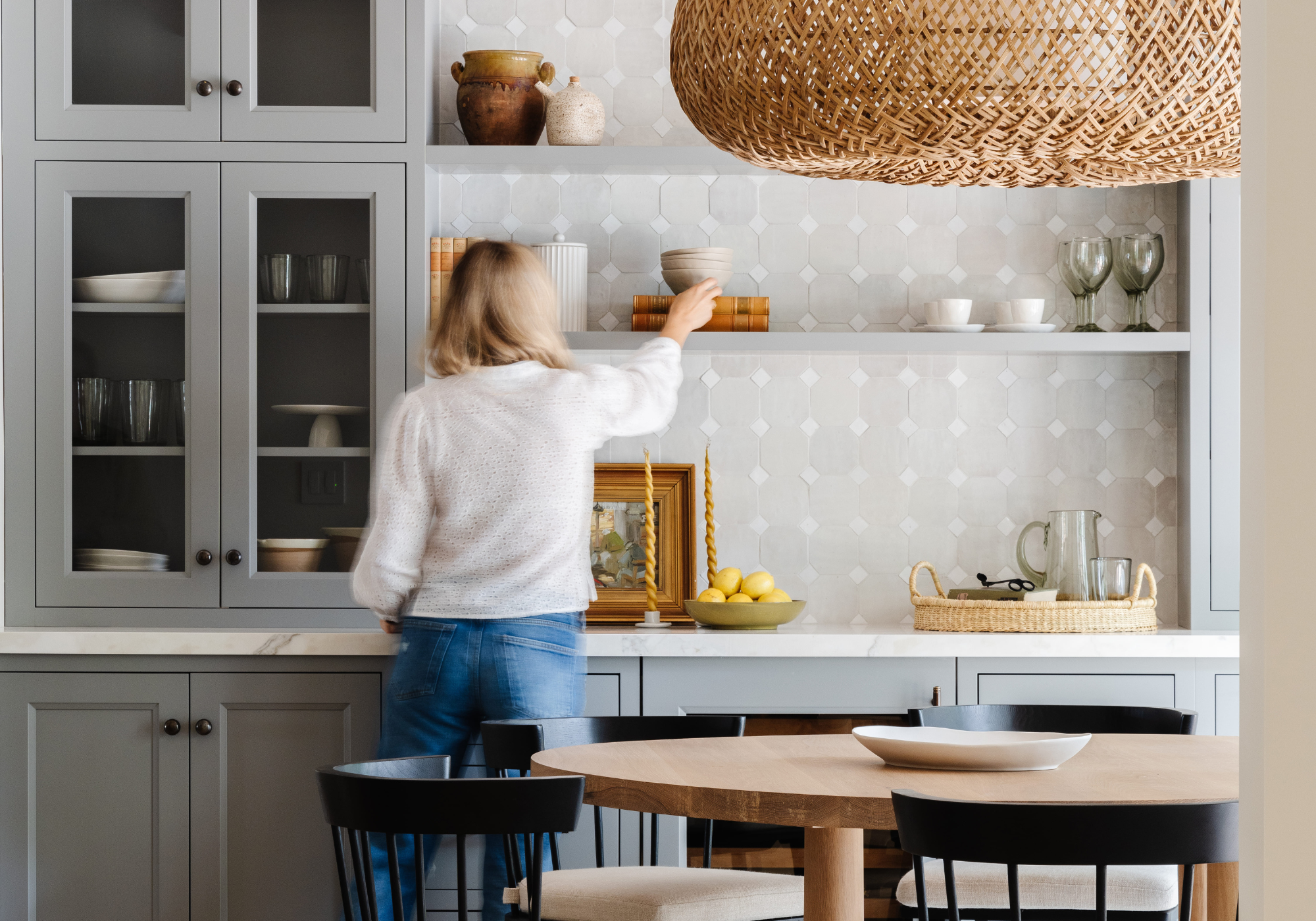 Calimia Home stylist arranging open kitchen shelves with ceramics during a styling service session