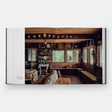 Calimia Home Summer by the Sea book open to a spread showing a wood-panelled cottage den lined with books.