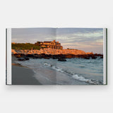 Calimia Home Summer by the Sea book open to a spread showing a cottage on the rocky Rhode Island coast at dusk.