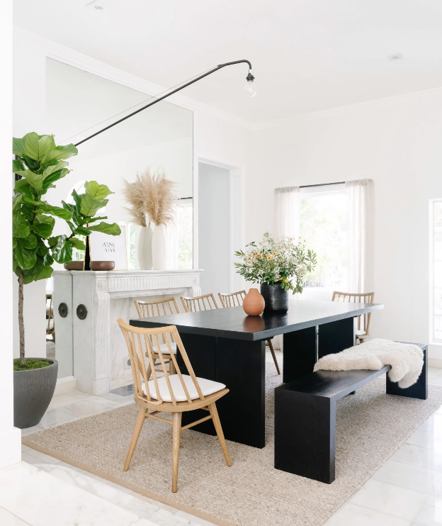 Casual dining corner with black table, spindle chair, and swing-arm sconce beside a fiddle-leaf fig