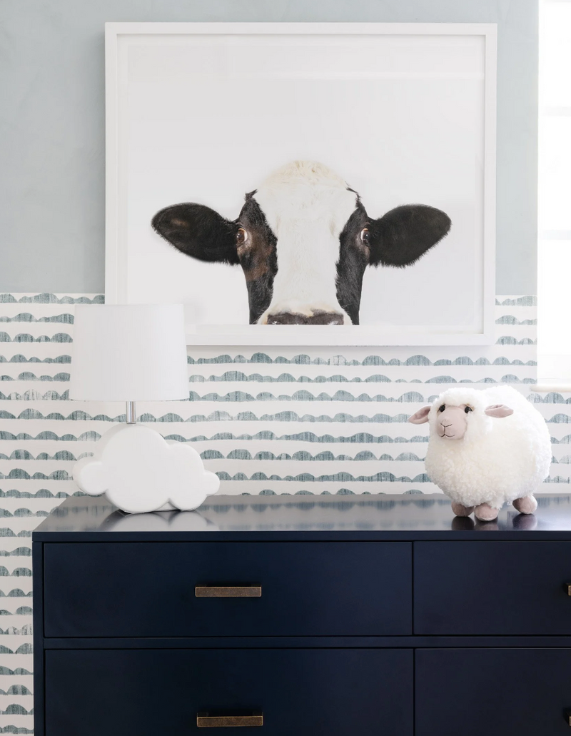 Holstein cow print and woolly sheep lamp atop a navy dresser in the nursery