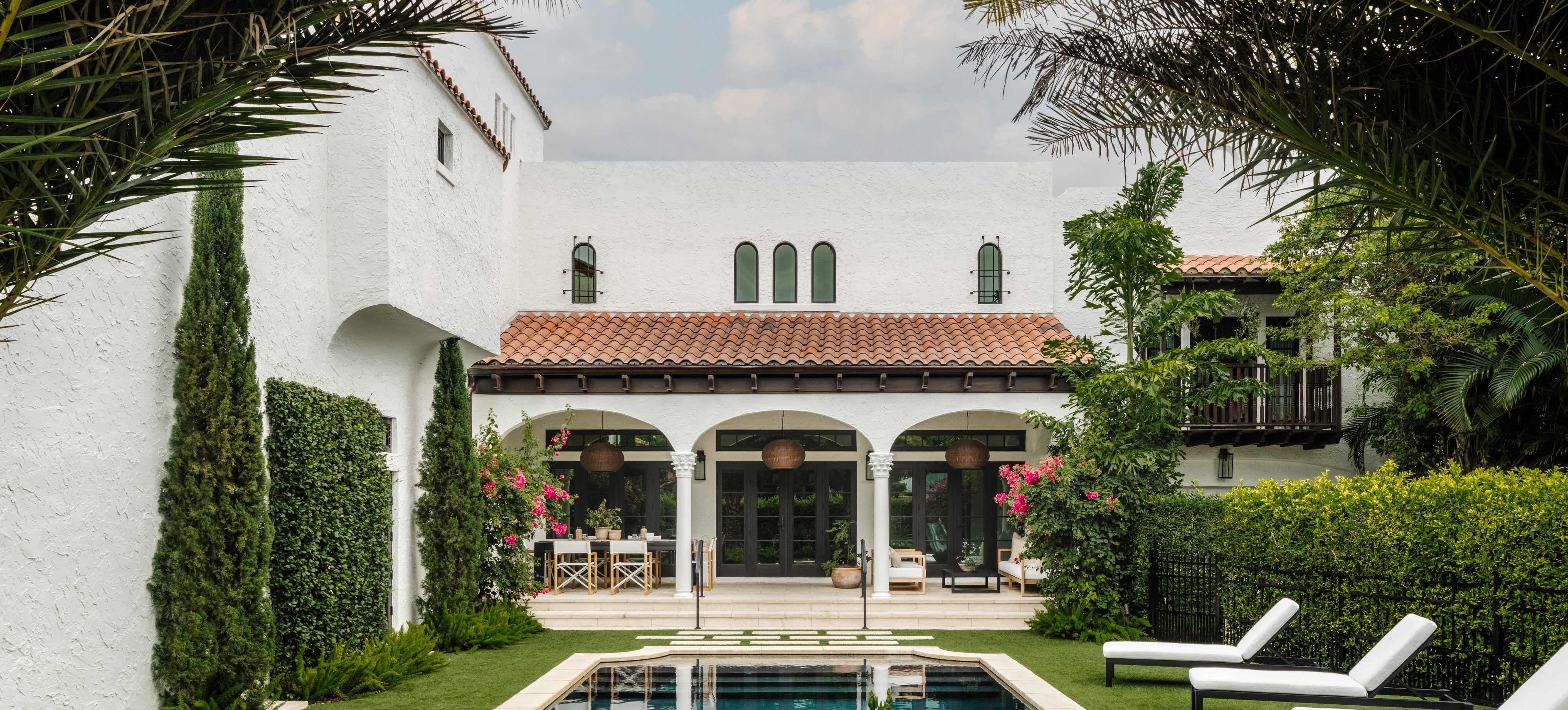 Mediterranean villa exterior with arched loggia, pool, and lounge chairs at Villa Belmonte, West Palm Beach