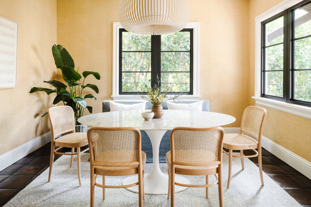 Breakfast room with round marble table, cane bistro chairs, and warm peach walls at Villa Belmonte
