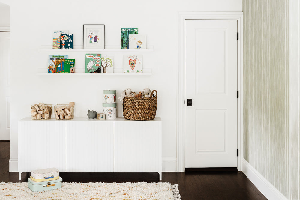 Children's room corner with picture-ledge bookshelves, fluted white cabinet, and woven basket