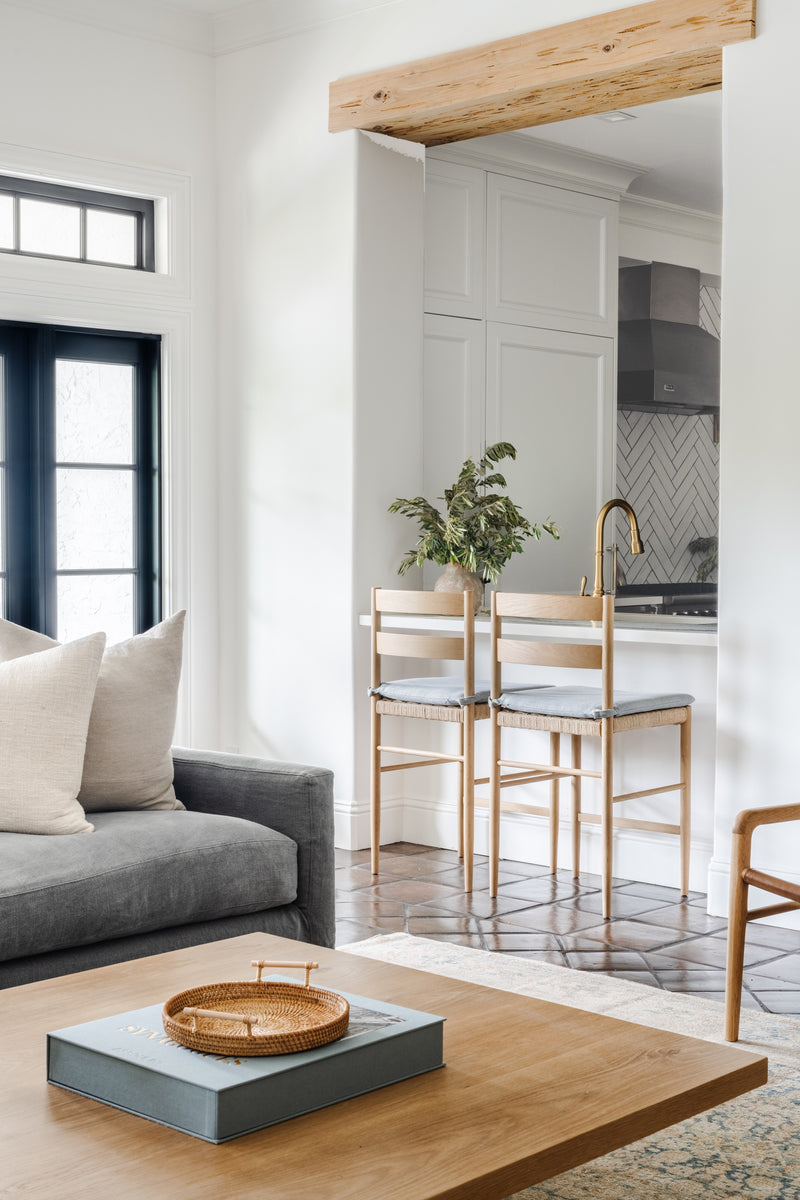 Brass counter stools at a kitchen pass-through with wood beam and terracotta tile floors