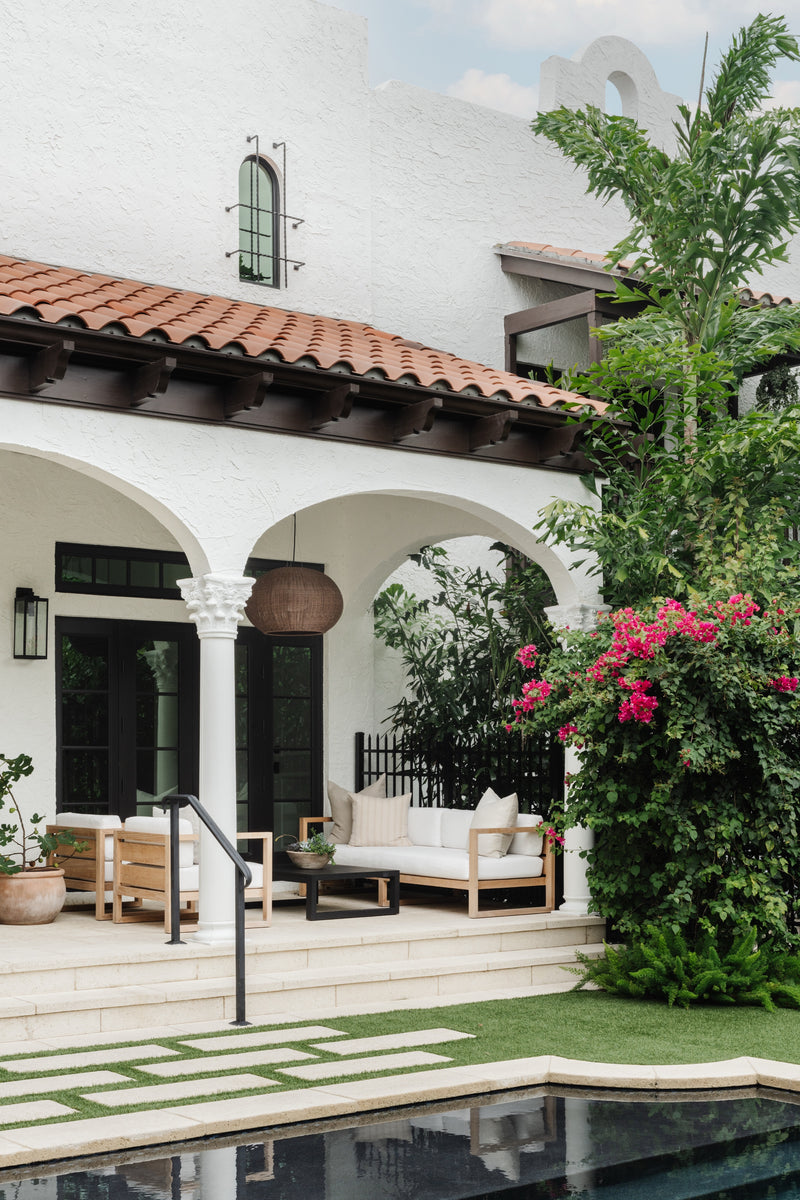 Covered patio with lounge seating and bougainvillea beside the pool, designed by Calimia Home