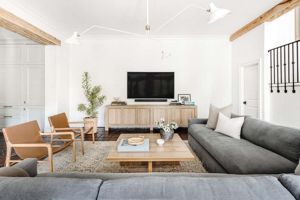 Family room with grey sectional, oak coffee table, and leather chairs in the West Palm Beach home