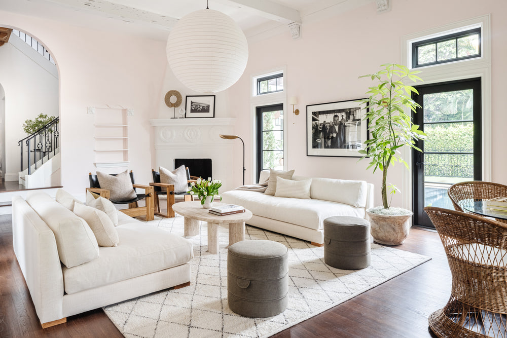 Light-filled living room with white slipcovered sofas and drum side tables in the Villa Belmonte residence