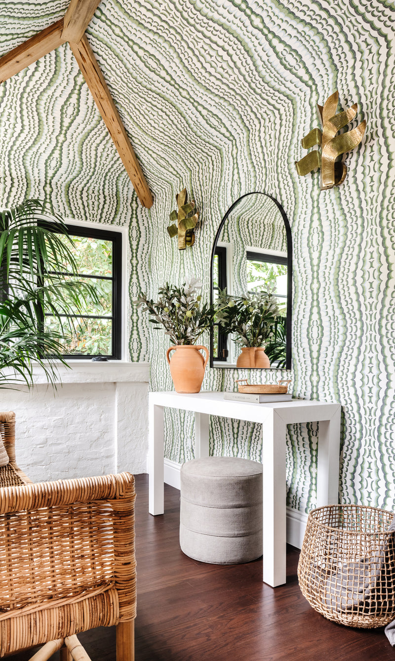 Powder room with wavy patterned wallpaper, arched mirror, white console, and woven baskets at Villa Belmonte
