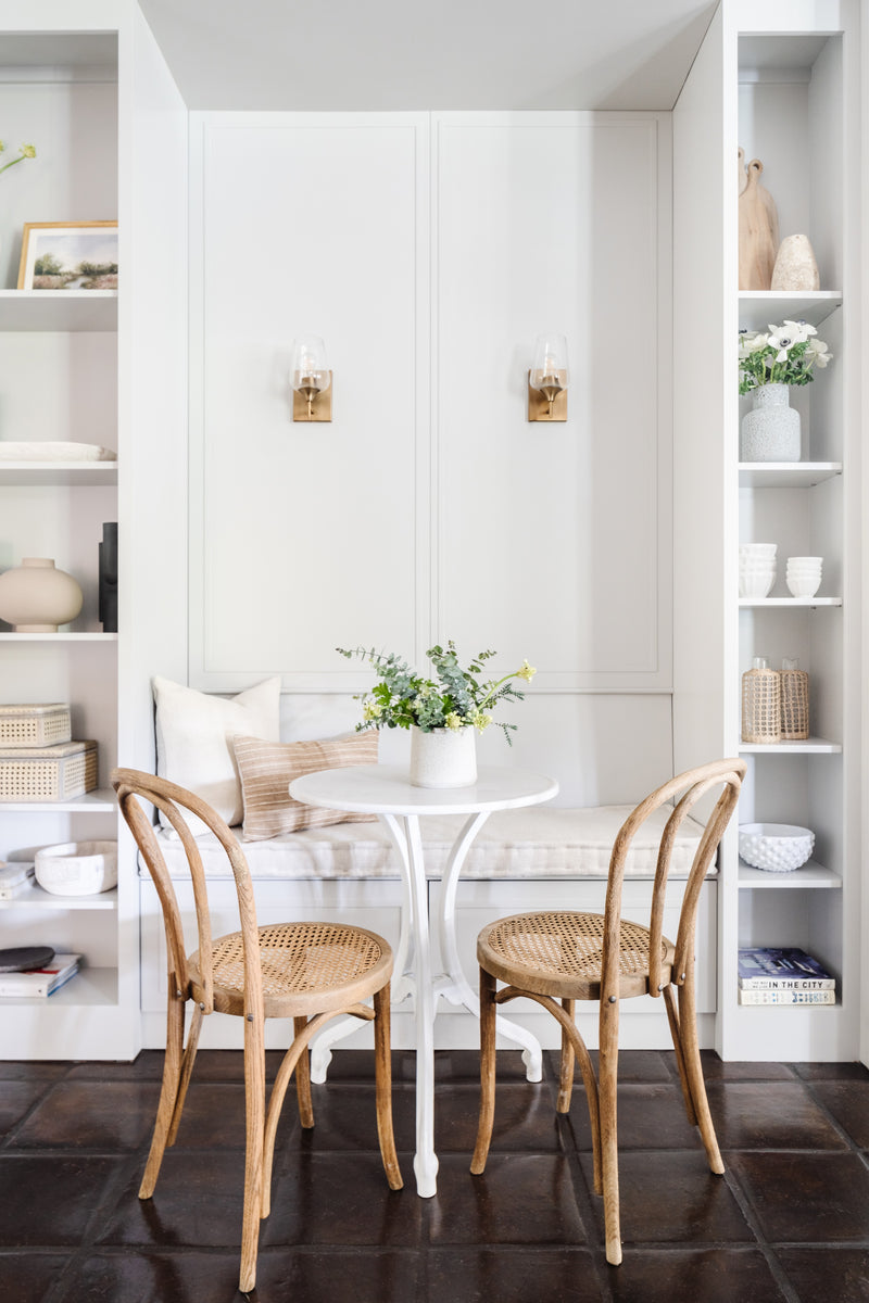 Breakfast nook with built-in banquette, white tulip table, and cane bistro chairs by Calimia Home