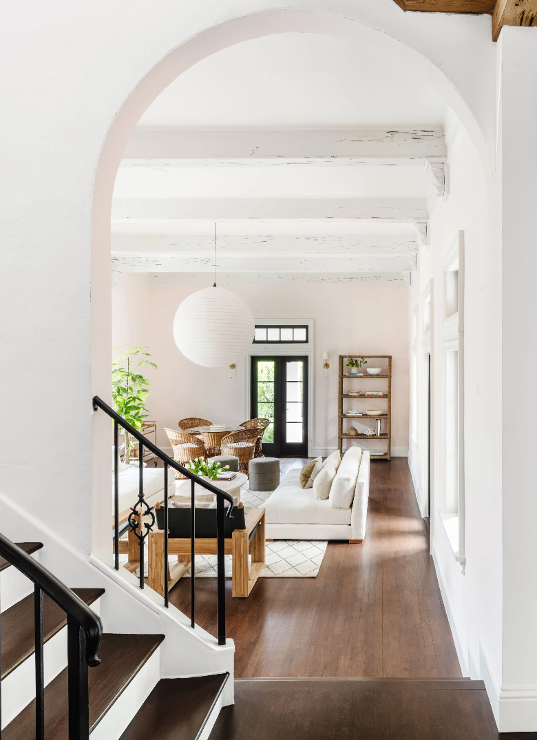 Staircase leading to a modern living room with white walls and wooden floors.