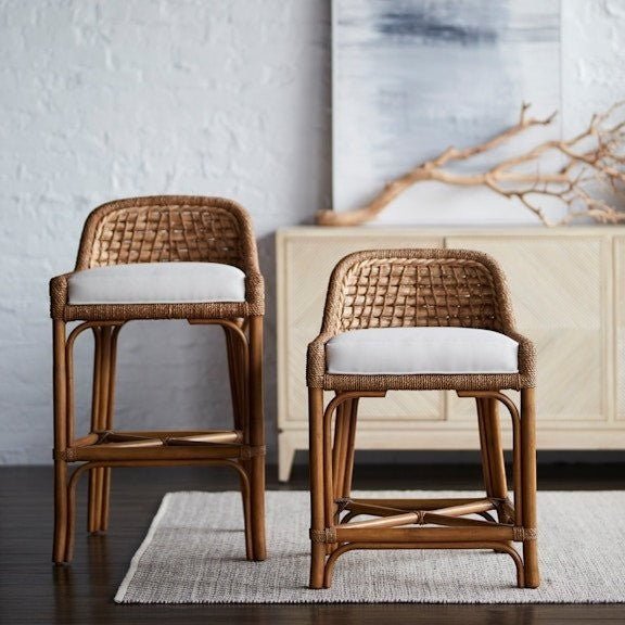 Calimia Home Capitola counter stool with natural rattan frame, seagrass weaving, and a white upholstered seat.
