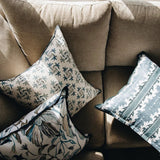 Maison Venu Celeste Lapis pillows with floral embroidery and ombré blue patterns arranged on a neutral sofa.