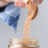 Calicutts cinnamon sugar blend being poured from a wooden spoon into a glass jar