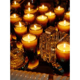 Many Climbing Tuscan Rosemary votive candles burn together in a warm tableau alongside a faceted crystal holder, casting amber light across the scene.