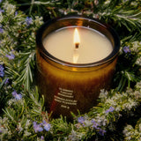 Flamingo Estate Climbing Tuscan Rosemary soy wax candle in a forest-green glass jar, surrounded by fresh rosemary sprigs.
