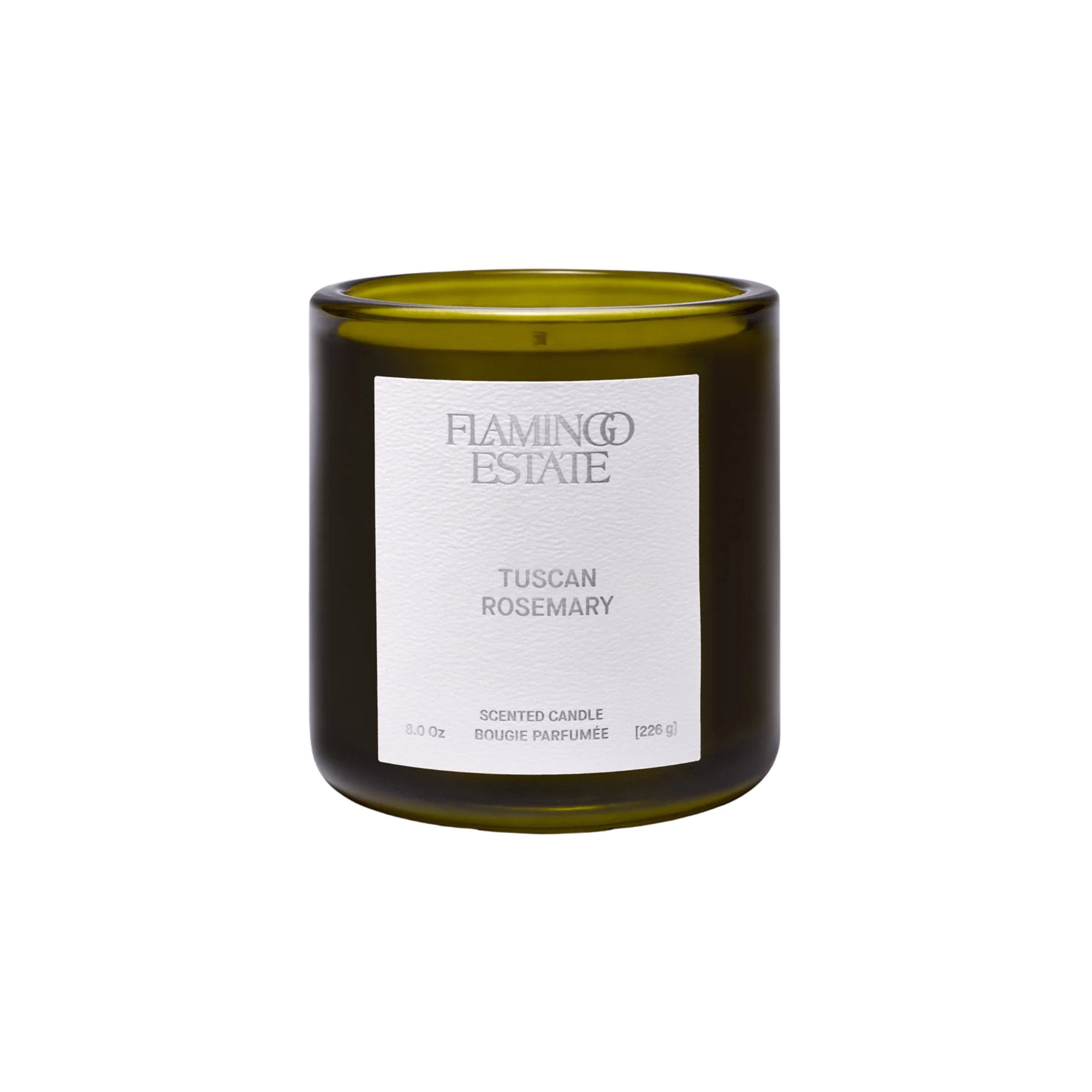 A green glass candle jar with a white label reads Flamingo Estate, Tuscan Rosemary Scented Candle, 8.0 oz, 226 g. The unlit candle sits on a white background, ready to fill your space with Mediterranean herb.
