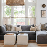 Calimia Home Cube Ottomans in nubby oatmeal linen placed in front of a grey sectional sofa in a bright living room