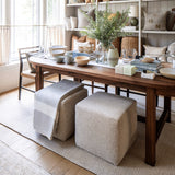 Calimia Home cube ottomans in nubby oatmeal Belgian linen tucked under a wooden dining table in a cozy living space.