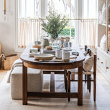 Calimia Home Cube Ottoman in nubby oatmeal Belgian linen tucked under a wooden dining table in a bright living space