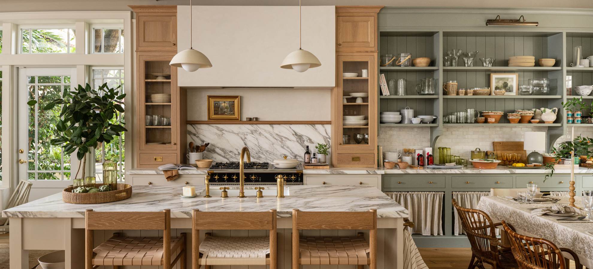 Kitchen display at Calimia Home Shop with marble island, wood cabinetry, and open shelves beside a set dining table in a warm-lived in space