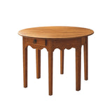 Calimia Home Demi Vintage Table in warm wood with a round top, scalloped apron, and a single drawer with ring pull.