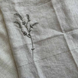 Close-up of the hand-embroidered branch motif on the Willow Stitch Apron, Belgian linen, One Bi One