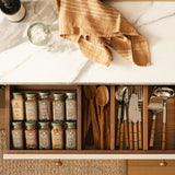 Sir Madam earth-toned linen jacquard tea towel draped over a kitchen drawer filled with spices and wooden utensils.