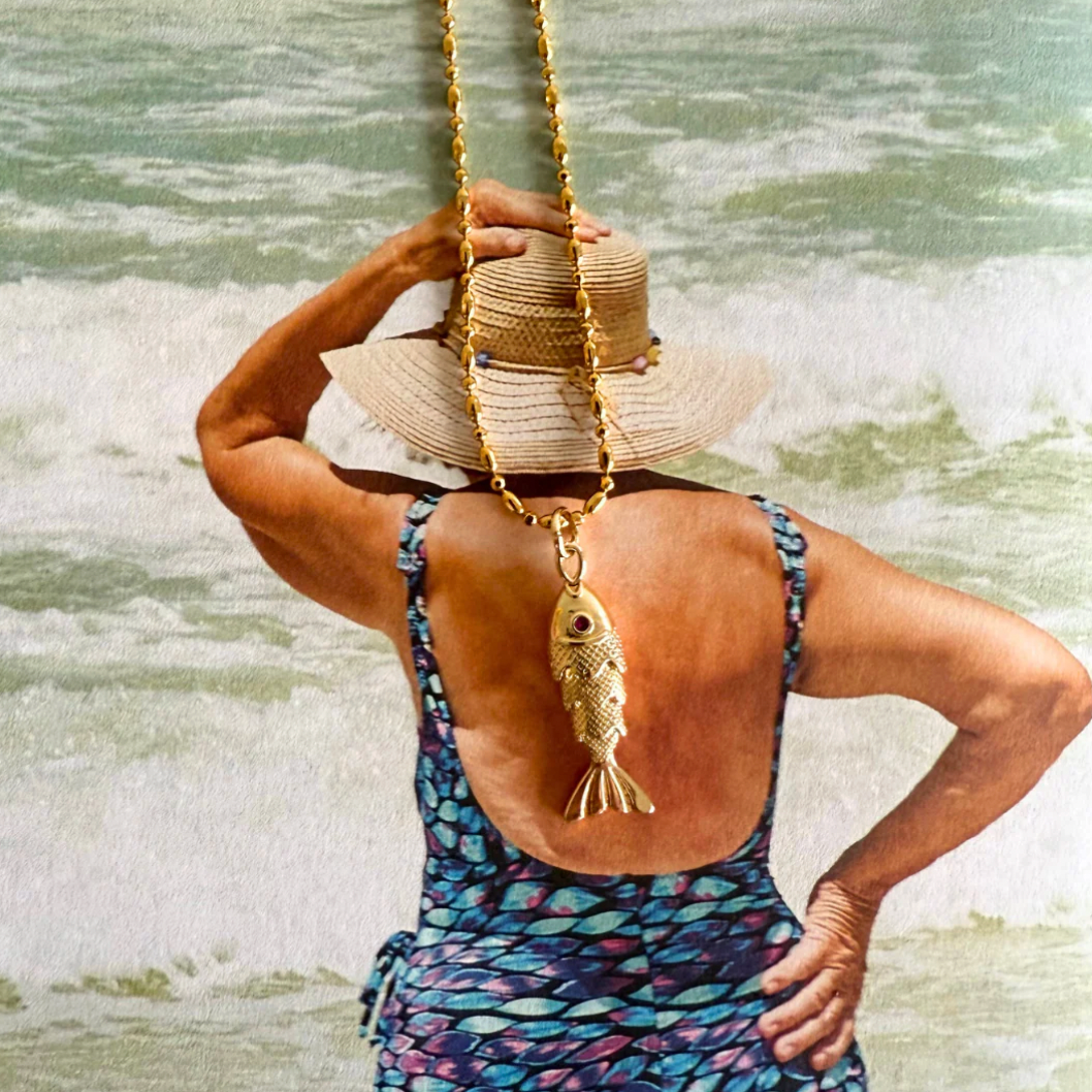 Close-up of fish bar pendant detail on gold textured chain