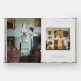 Calimia Home Everybody Loves Stripes book open to a spread showing a green drawing room with striped armchairs and a bust.