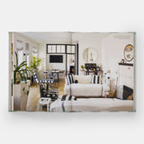 Calimia Home Everybody Loves Stripes book open to a spread showing a bright living room with black and white striped upholstery.