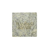 A pale square Flamingo Estate Exfoliating Peppermint Organic Bar Soap embossed with the brand wordmark, flecked with blue clay and sea salt, on a white background.