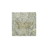 A pale square Flamingo Estate Exfoliating Peppermint Organic Bar Soap embossed with the brand wordmark, flecked with blue clay and sea salt, on a white background.