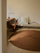 Armadillo Braid Rug in Persimmon, hand-braided wool blend rug shown in a room setting