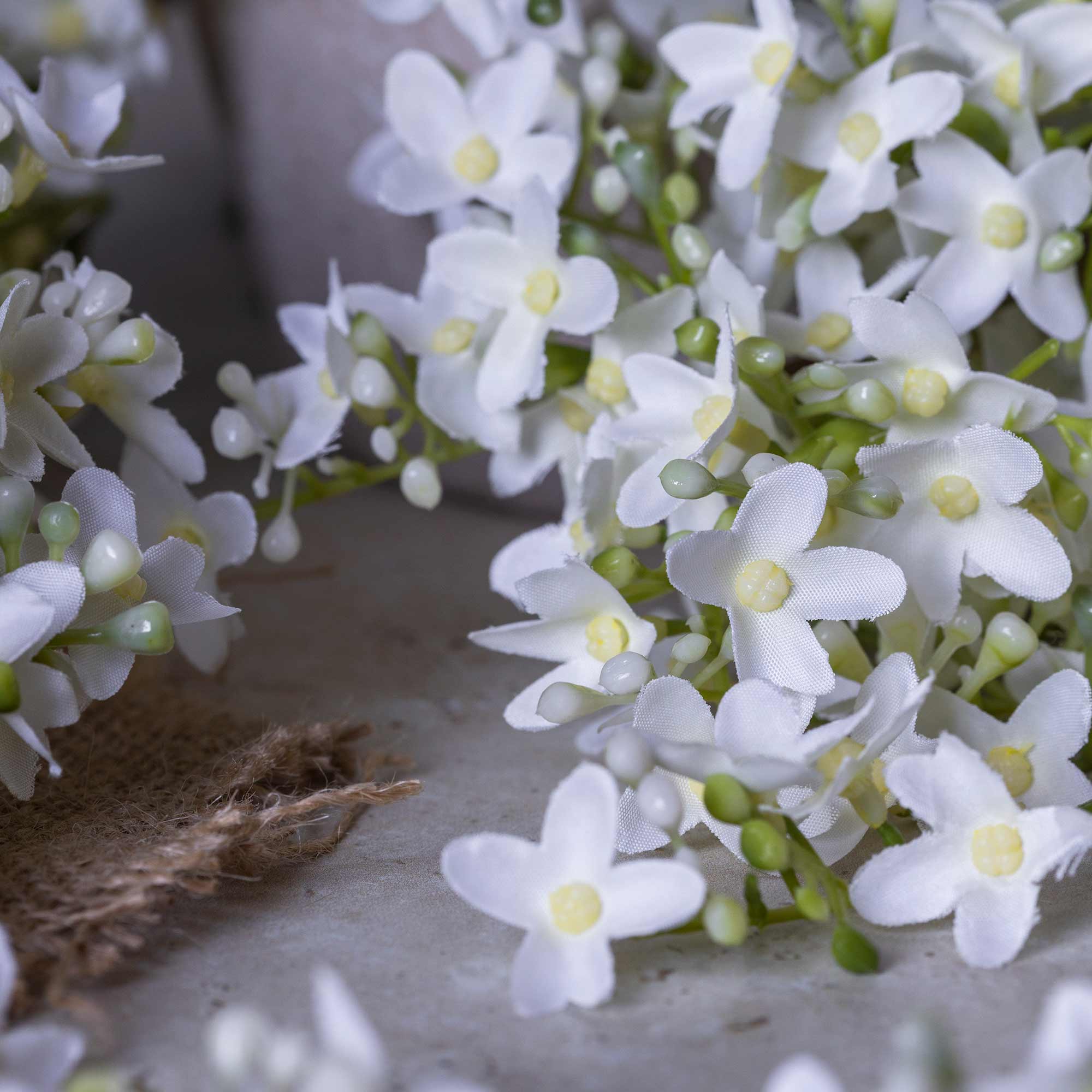 Faux lilac stems styled in a tall pottery vase with rustic ceramic companion vessel, white faux flower interior styling