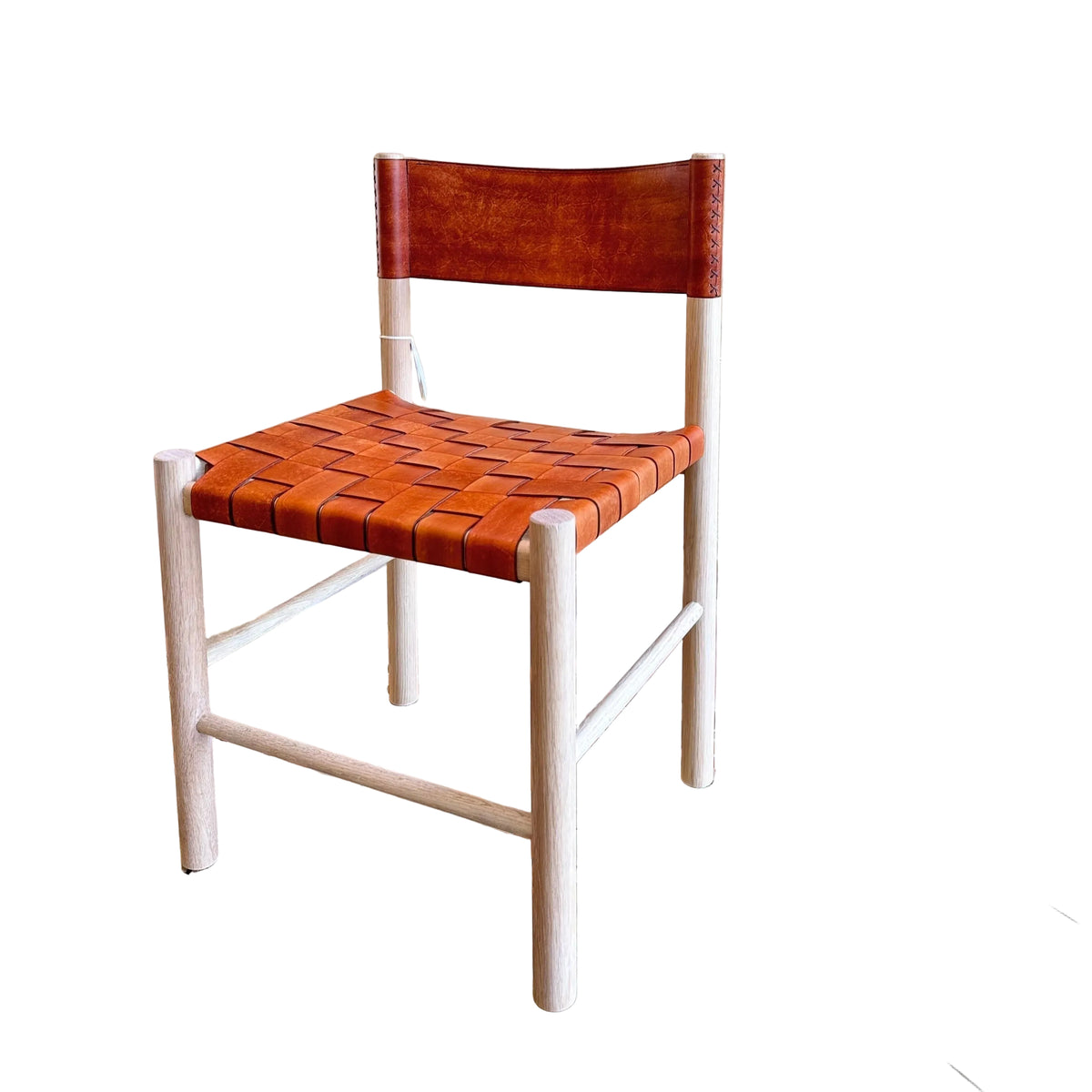 A wooden dining chair with a woven orange-brown leather seat and backrest, set on a patterned tile floor against a stucco wall.