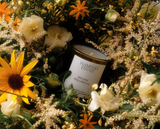Flamingo Estate Golden Pollinator Candle surrounded by flowers, lifestyle styling