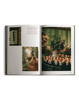An interior spread of the Flamingo Estate cookbook displays a glowing wall of lit candles surrounding a wildflower bouquet at the Los Angeles estate.