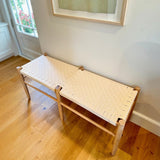 Calimia Home Gaon bench featuring a solid white oak frame and a handwoven white canvas ribbon seat in a bright room.