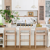 Calimia Home Gaon counter stools with white oak frames and woven natural leather seats in a bright modern kitchen.