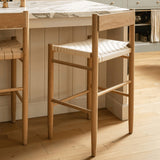 Calimia Home Gaon counter stool featuring a solid white oak frame and a woven natural leather seat in a kitchen.