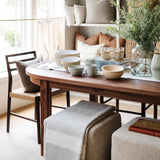 Long Hood Chandelier in white oak above a walnut table with a Glenmore Woven Dining Chair and pillow shelves